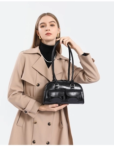 Detail of black wax leather bowling bag with twin front pockets on camel trench coat