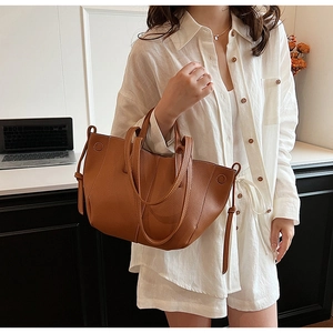 Caramel brown leather tote bag with drawstrings shown with casual white outfit