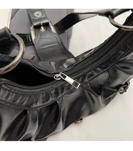 Détail du zip argenté et du cuir froissé sur un sac à bandoulière noir brillant