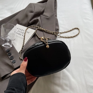 Detail of black quilted leather crossbody bag with golden chain and ball clasp