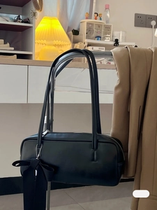 Detail view of black matte leather shoulder bag with a silk ribbon bow and silver zipper
