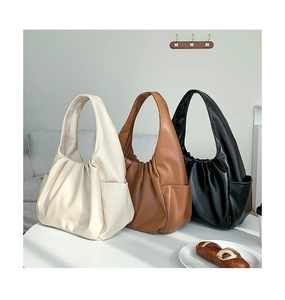 Detailed side view of pleated hobo bags in white, brown, and black on a table