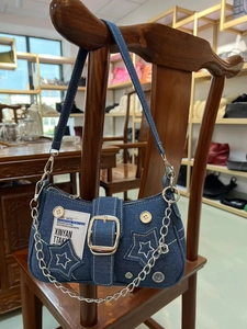 Detail of star denim underarm bag with retro buttons, metal chain and silver buckle