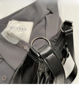 Détail de la boucle argentée et du cuir noir plissé vintage sur un sac fourre-tout