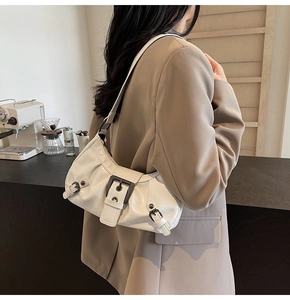 White crescent underarm bag with pleats and buckle shown on a model in a cafe