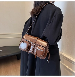 Detail of vintage brown shoulder bag with multiple zippers and adjustable strap worn by model