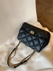 Detail of black quilted leather shoulder bag with gold chain strap and metal swivel lock