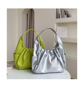 Detail of lime green and silver pleated hobo bags with side pockets in a home setting