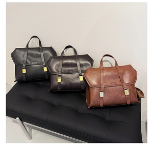 Three vintage leather messenger bags in black, deep brown, and caramel colors on a bench
