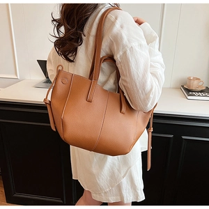 Detail of caramel leather tote bag with white contrast stitching and drawstring accents