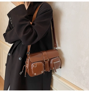 Detail of vintage brown leather shoulder bag with functional pockets and silver zippers