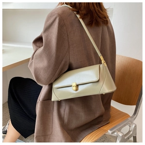 Detail of light green patent leather baguette bag with gold metal buckle on shoulder
