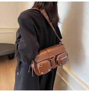 Macro detail of the brown leather shoulder bag featuring silver zippers and metallic buckles