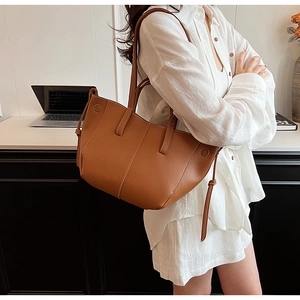 Detail of brown pleated tote bag with lychee texture leather and drawstring accent