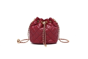 Detail of burgundy quilted leather bucket bag with gold-tone chain drawstring and texture