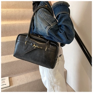 Vue détaillée du sac Boston en cuir noir avec boucle dorée vintage et texture lisse