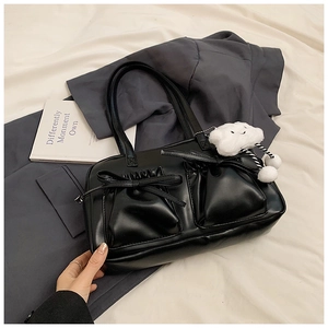 Detail of black PU leather tote bag with bow tie pockets and cloud plush charm