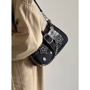 Detail view of denim underarm bag featuring star patches and chunky metal hardware accents