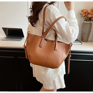 Detail of caramel brown lychee grain leather tote bag with stylish side tie decoration