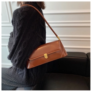 Close-up of a vintage brown leather underarm bag featuring a golden square metal buckle