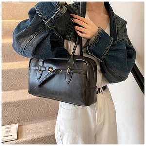 Vue détaillée d'un sac Boston vintage noir avec anneaux dorés et cuir au fini lisse et brillant
