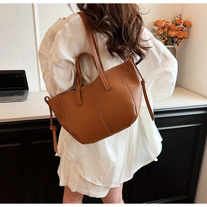 Detailed view of caramel leather tote bag with white stitching and round craft detail