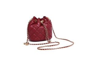 Close-up of a burgundy quilted bucket bag with gold chain strap and drawstring closure