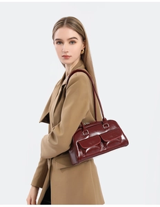 Detail of burgundy waxed leather shoulder bag with double front flap pockets and zippers