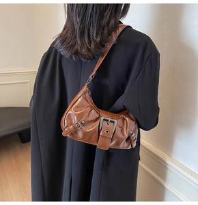 Detail of dark brown glossy leather underarm bag with vintage buckle and pleated texture
