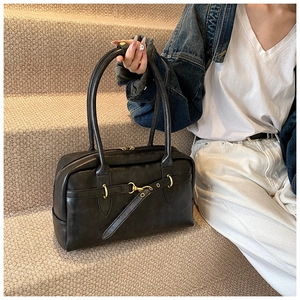 Détail du sac Boston vintage en cuir noir avec boucle dorée et fines anses doubles