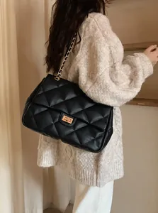 Close-up of classic black quilted shoulder bag with gold chain strap and turn-lock