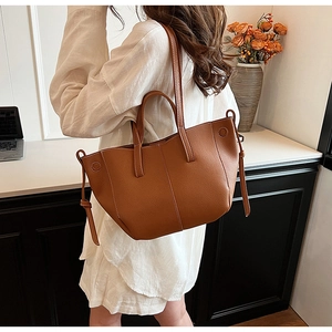 Detailed view of brown lychee texture leather tote bag with side drawstring accents