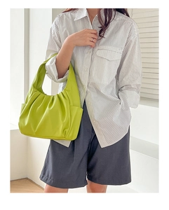 Close-up of bright green ruched cloud bag showing soft leather texture and side pocket