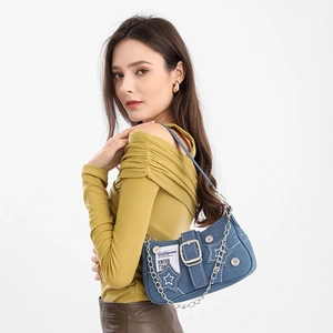 Detail of star denim underarm bag with decorative metal chains and brand tag texture