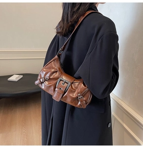 Side view of brown pleated crescent underarm bag showing silver metal buckle detail