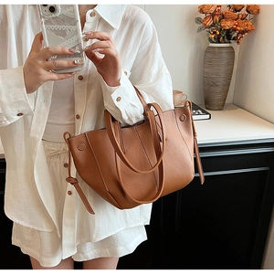 Detail of brown lychee grain leather tote bag with long handles in a stylish home setting