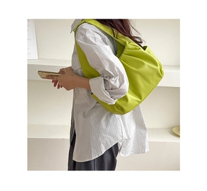 Detail of bright green croissant shoulder bag with pleated texture on model side profile