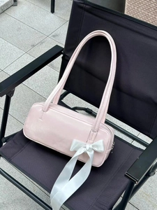 Pink rectangular underarm bag with a white satin bow detail on a black chair