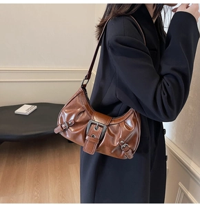 Detail of vintage brown pleated hobo bag with metal buckle on a model's shoulder