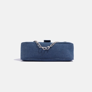 Detailed close-up of dark blue denim star bag with silver metal chain on grey background