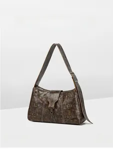Macro shot of vintage brown leather tote bag featuring aged gold buckles and studs