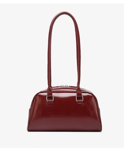 Detailed view of glossy oil wax leather finish and silver buckles on the maroon handbag