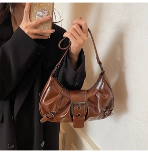 Detail of dark brown pleated underarm bag with vintage metal buckle on black suit