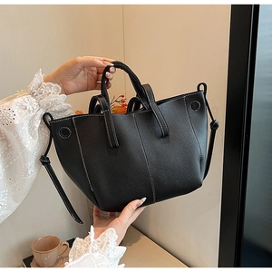 Detail of black tote bag with lychee texture, contrast white stitching and round handles