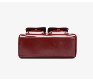 Detail of burgundy wax leather handbag featuring double pockets and vintage glossy texture
