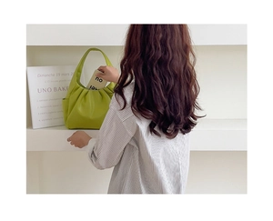 Detail of avocado green pleated crescent bag showing soft synthetic leather texture