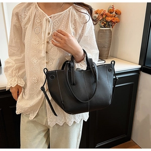 Detail of black pebbled leather tote bag with white contrast stitching and shoulder strap