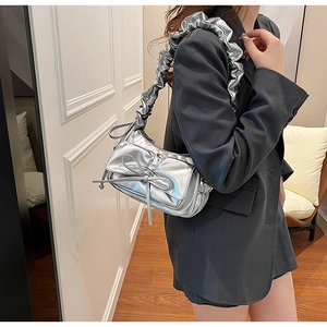 Detail of silver metallic cloud bag with ruched strap and bow decoration on model