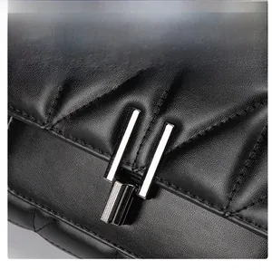 Detail of midnight black quilted leather texture and metallic clasp on crossbody bag