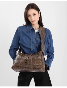 Detail of vintage brown leather tote bag with distressed texture and metal buckle accents